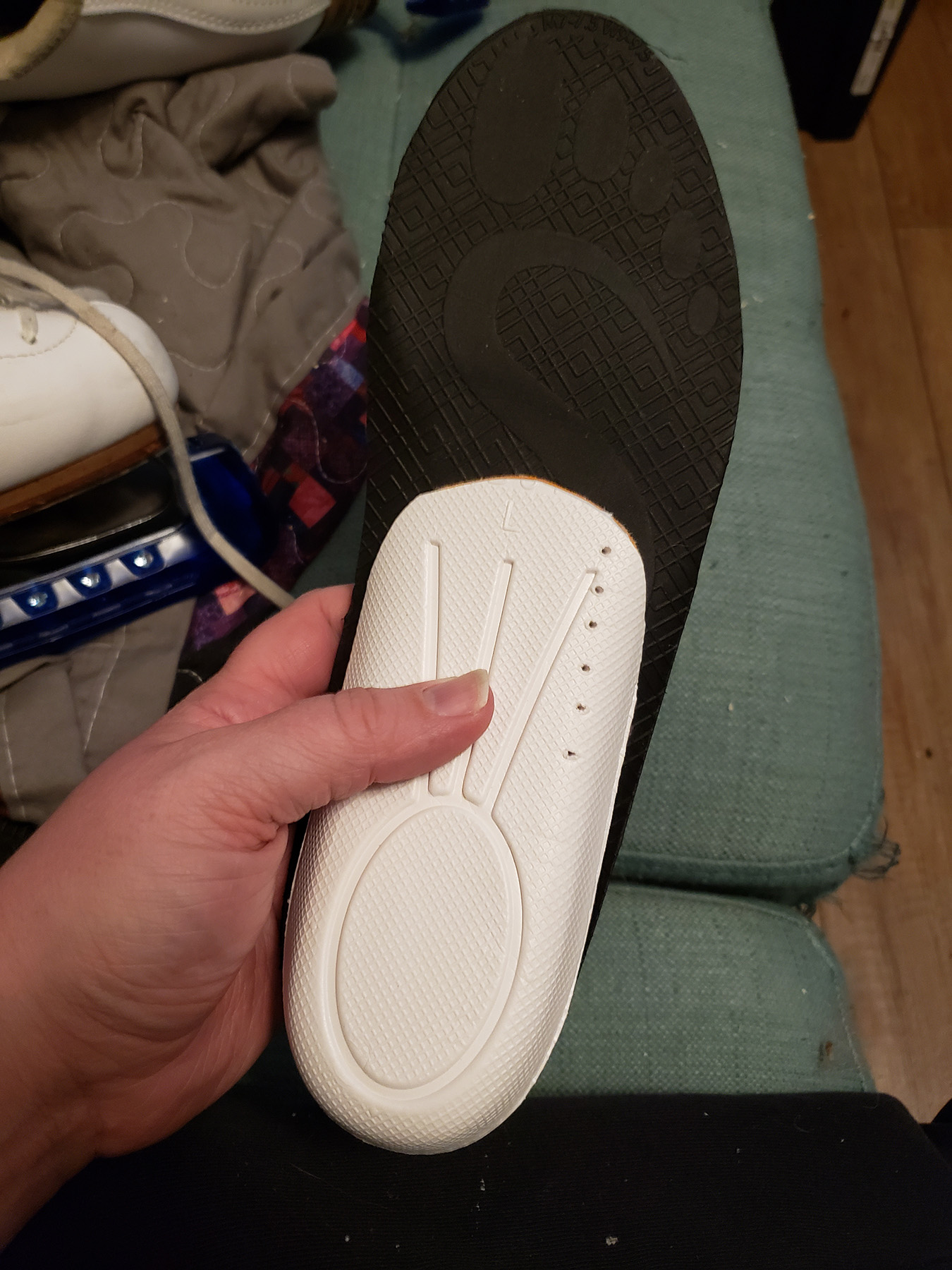 Underside view of a heel lift being held under an arch support insole.