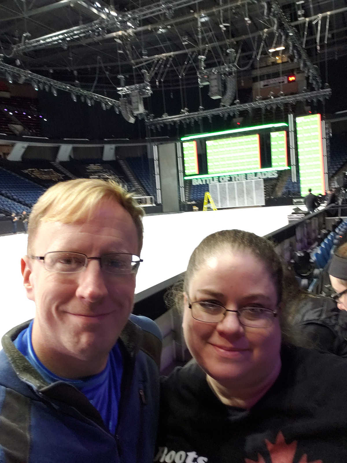 A middle aged couple taking a selfie in front of a rink.