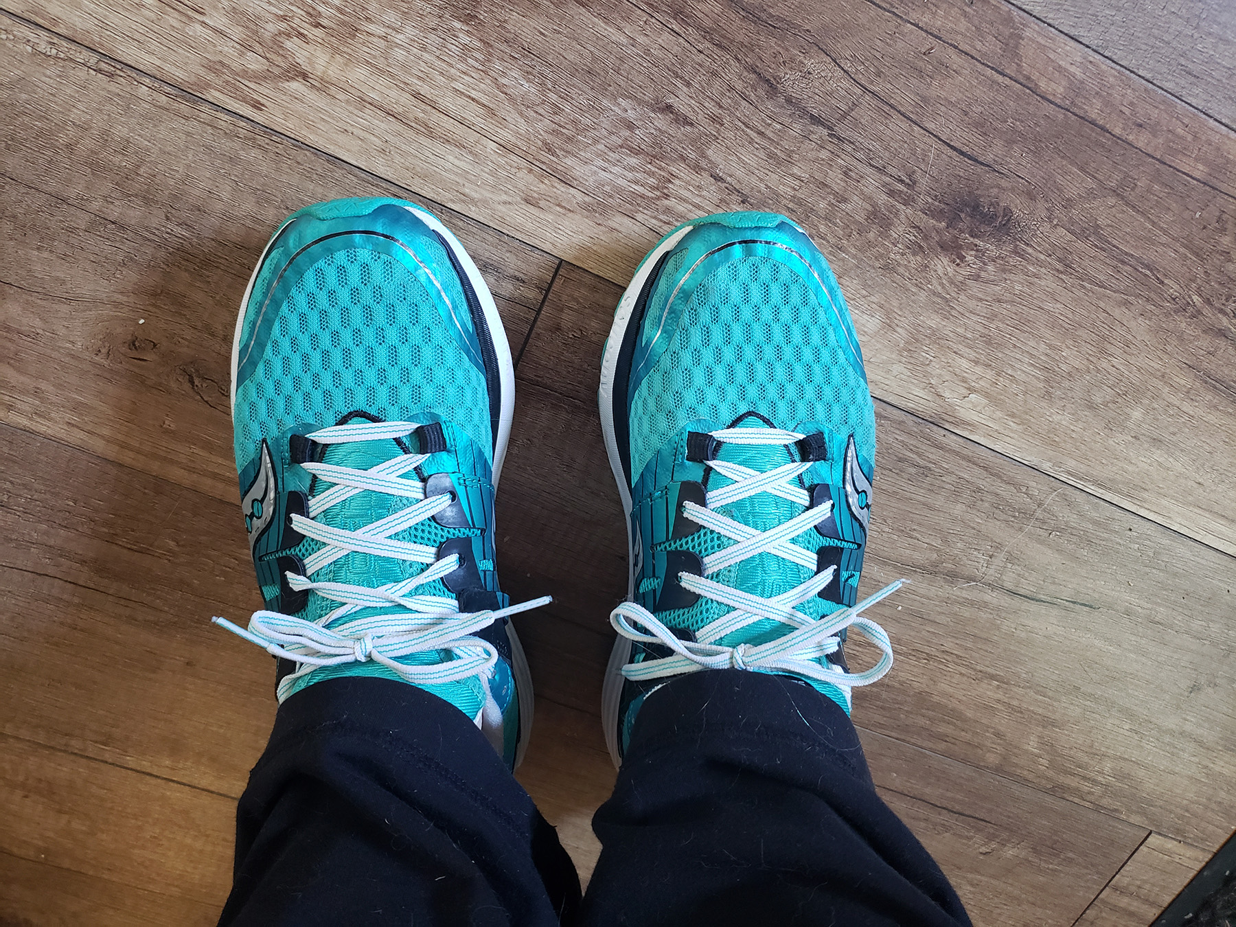 A pair of feet with green running shoes on.