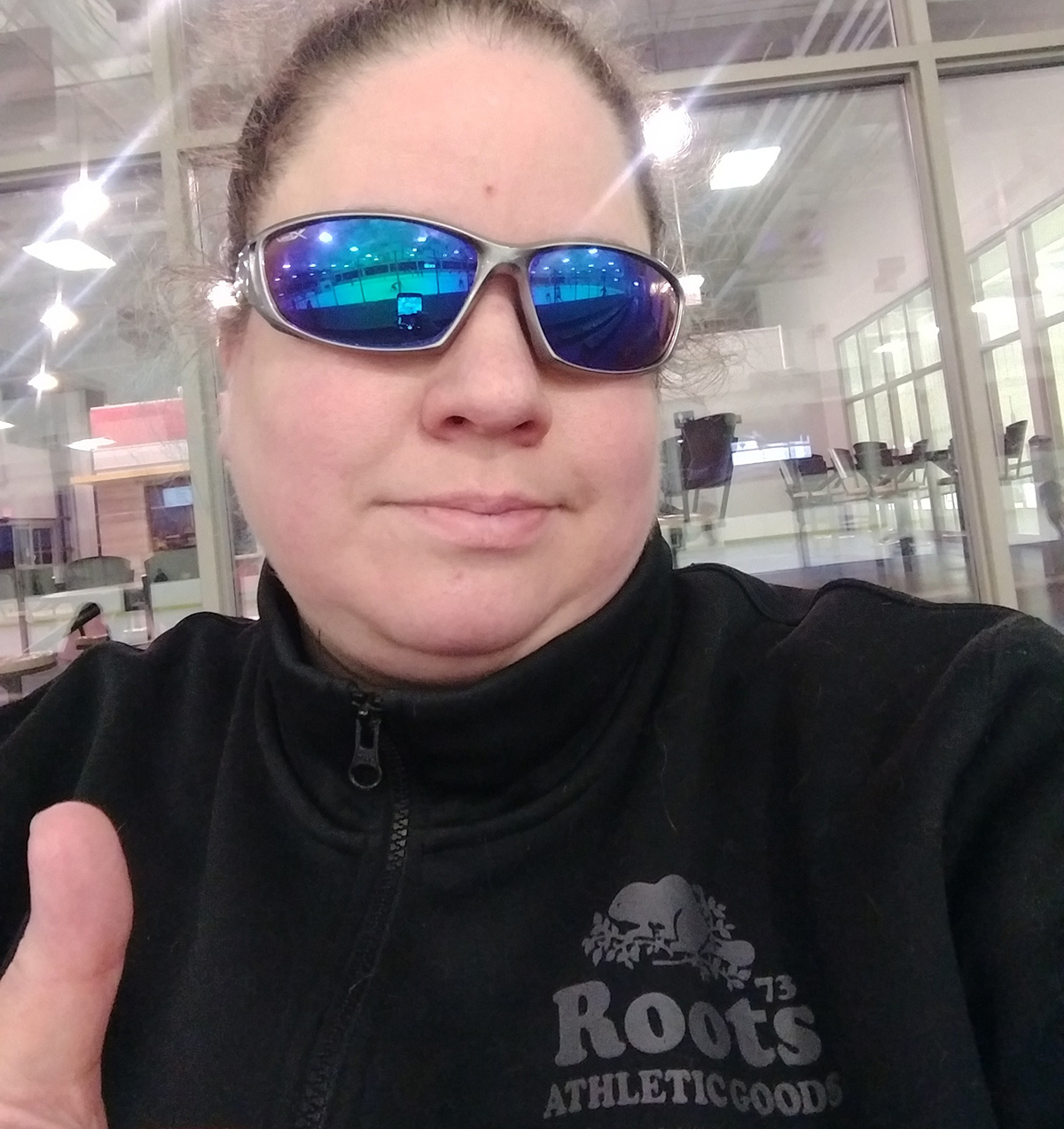 A woman in sunglasses giving a thumbs up