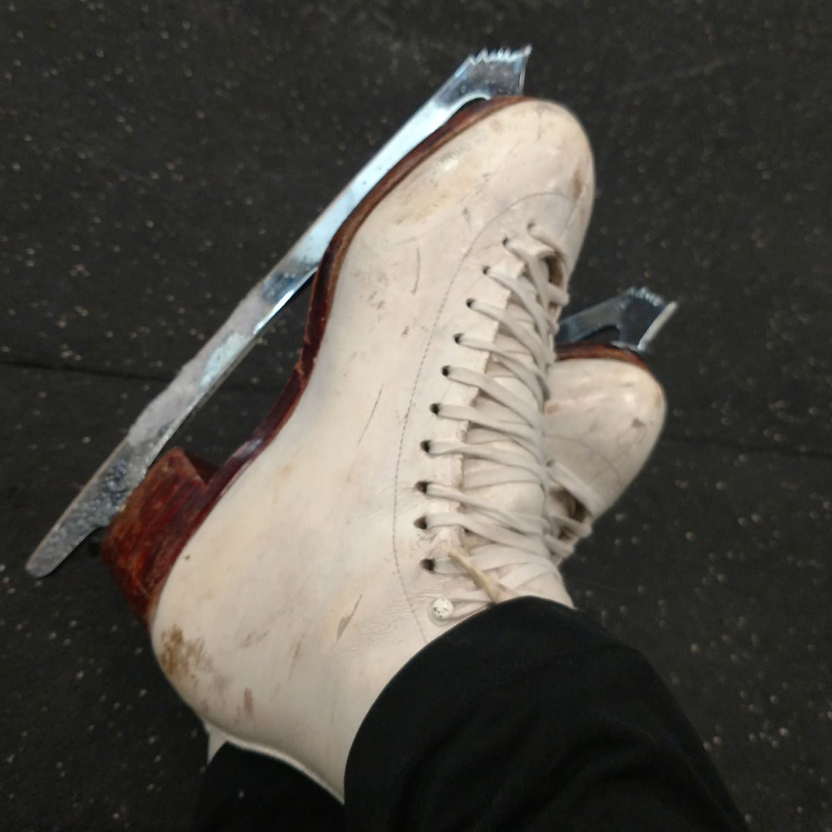 A pair of used skates on crossed feet.