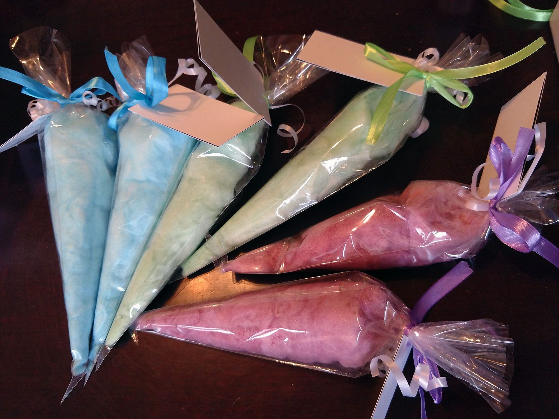 Blue, green, and purple bags of cotton candy, each tied with matching ribbon and a card.