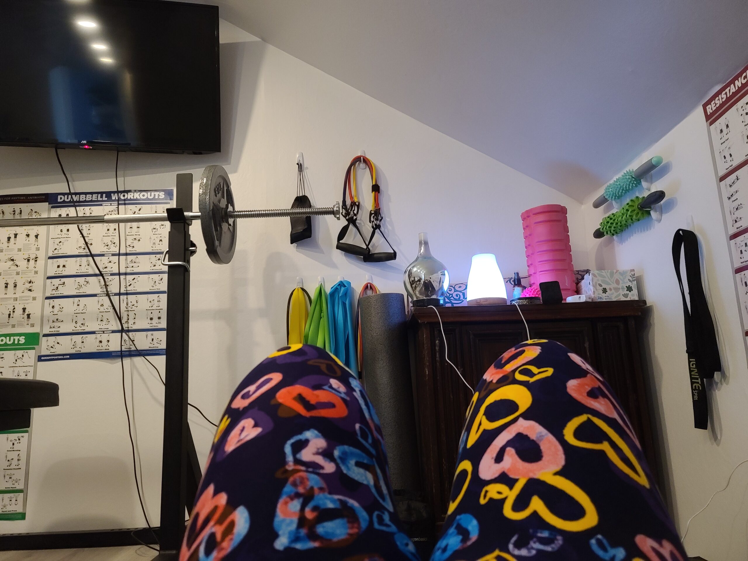 A view of a home gym, over knees clad in colourful tights.