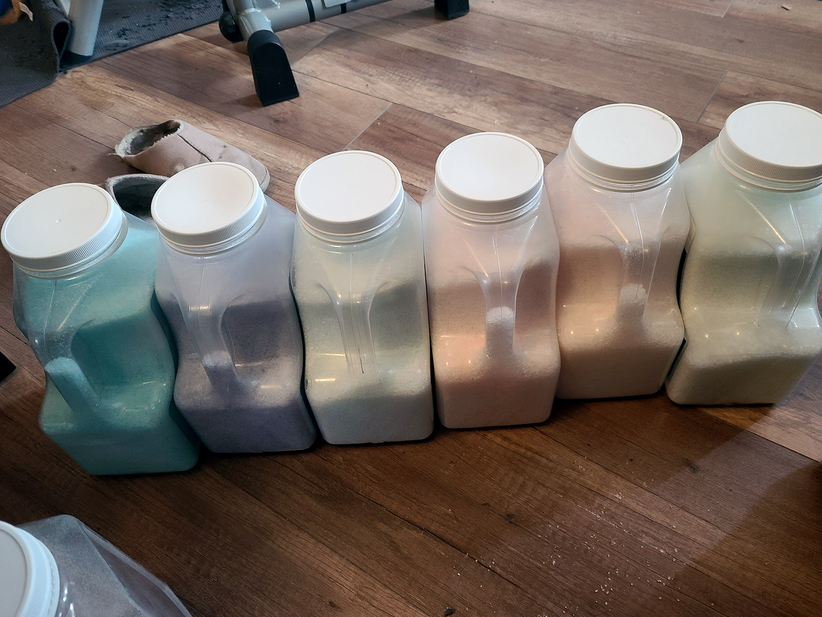 A line of jugs filled with coloured epsom salt.