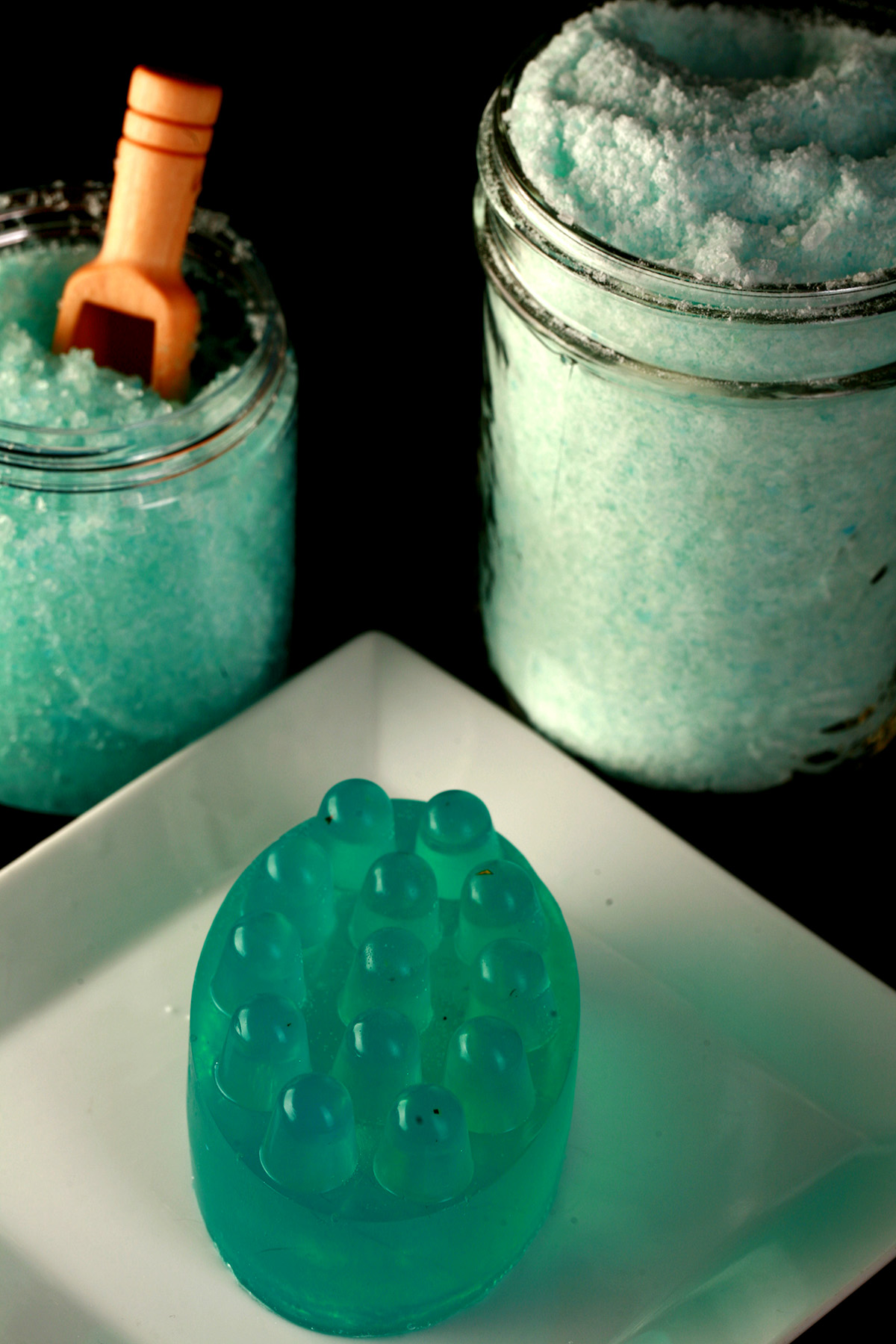 An arrangement of a blue nubby soap, a blue salt scrub, and a jar of bath salt.