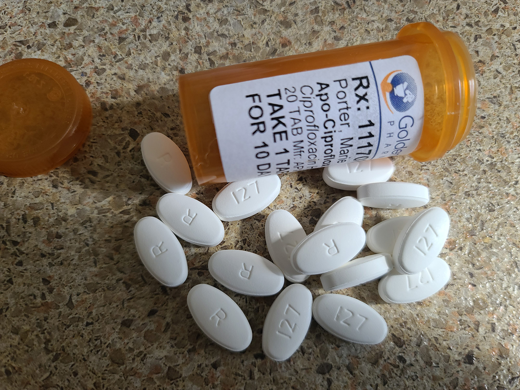 A bottle of ciprofloxacin with the pills spread out in front of it.