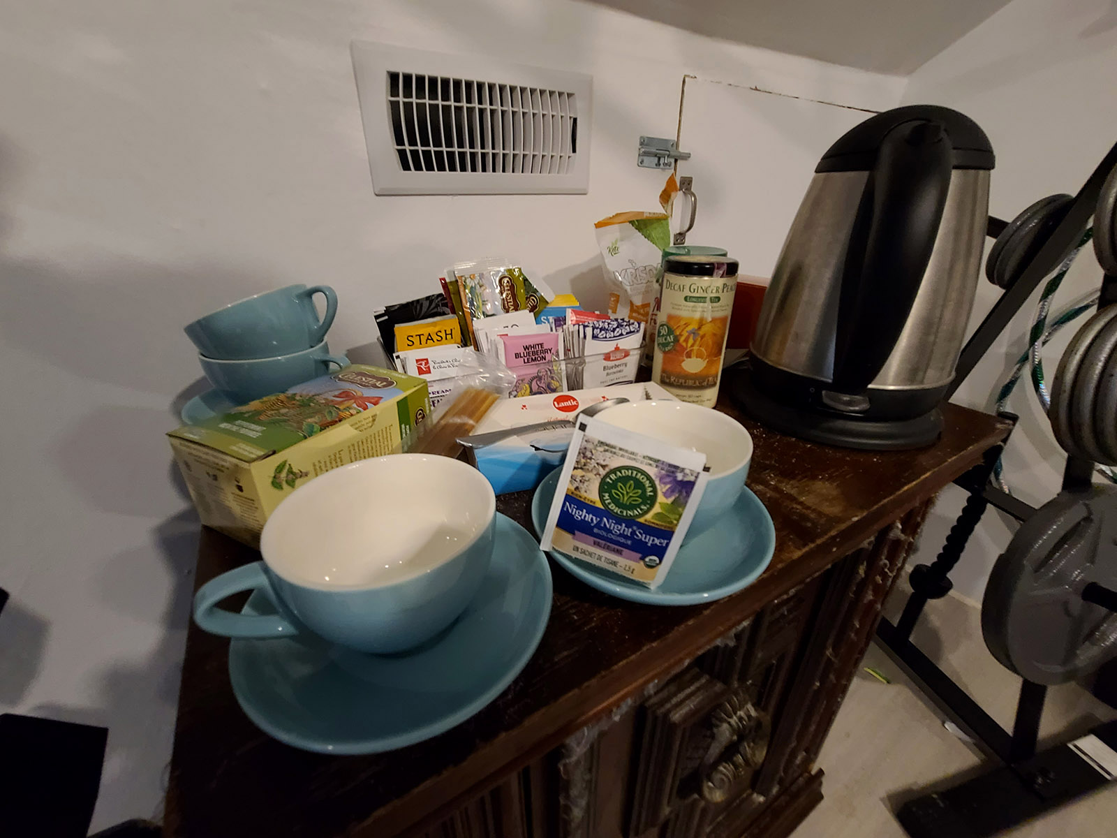 Various teas, tea mugs, and an electric tea kettle on a small table.