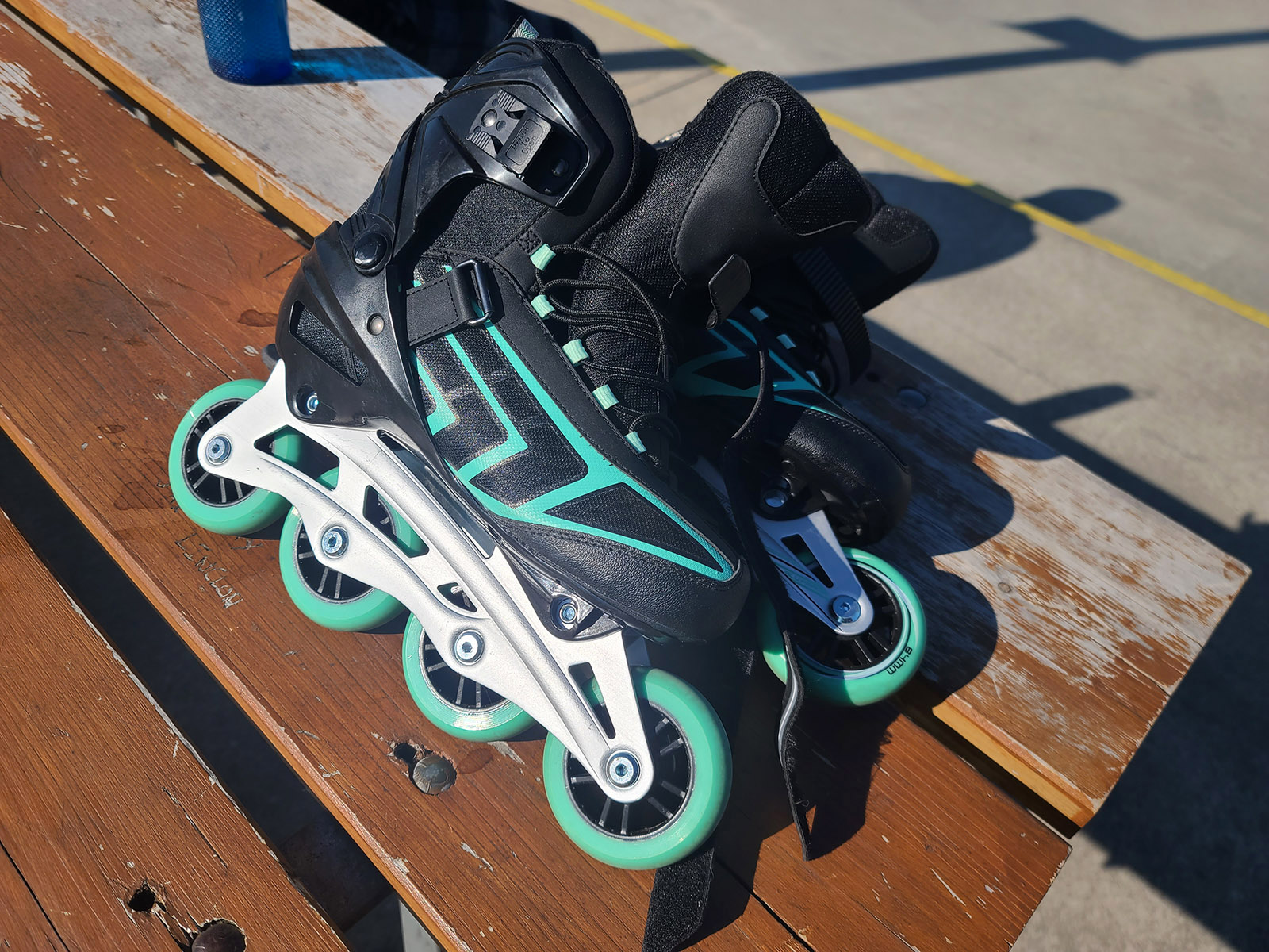 A pair of black and green recreational inline skates on a picnic table.